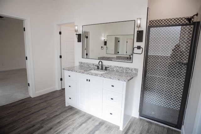 bathroom with walk in shower, vanity, and hardwood / wood-style flooring