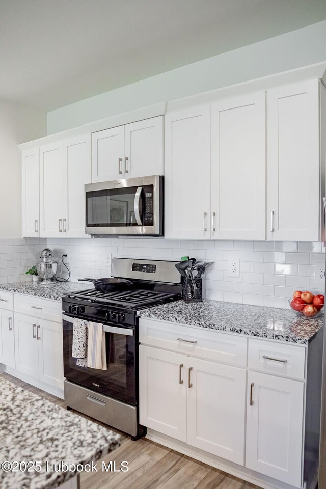 10517 Albany Ave, Lubbock, TX 79424 - kitchen featuring stainless steel appliances, light stone counters, white cabinets, and backsplash