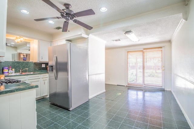 kitchen with visible vents, a sink, dark countertops, white cabinetry, and stainless steel fridge