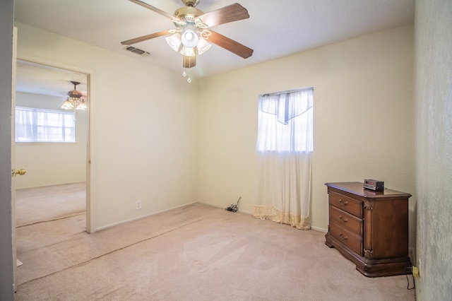 spare room featuring visible vents, light colored carpet, and ceiling fan