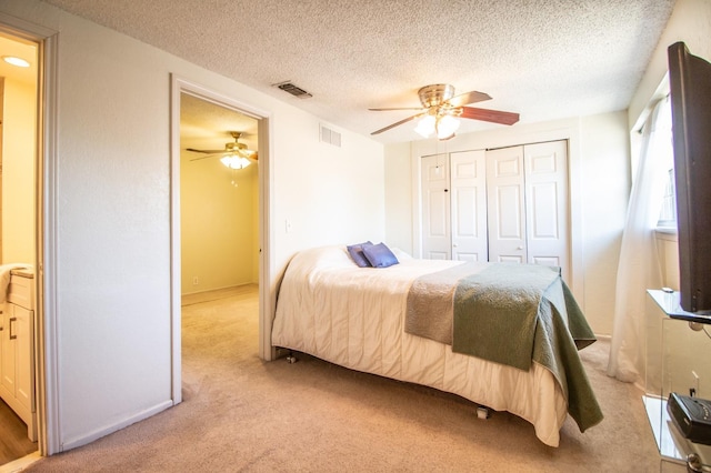 bedroom featuring a closet, visible vents, light colored carpet, and a textured ceiling