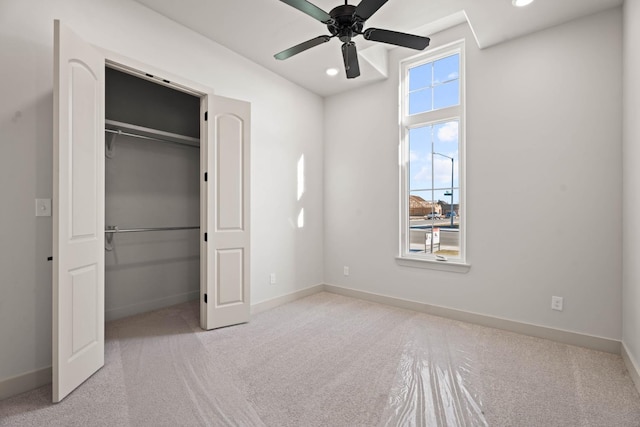 unfurnished bedroom with ceiling fan, a closet, light carpet, and a walk in closet