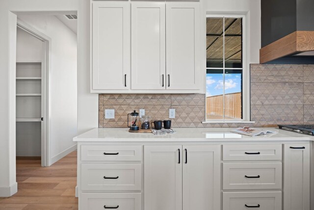 kitchen with premium range hood, light hardwood / wood-style floors, and white cabinets