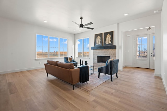 living room with ceiling fan, a fireplace, and light wood-type flooring