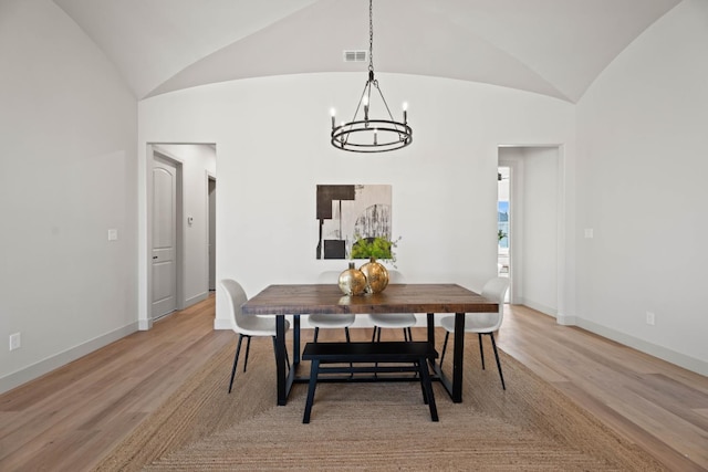 dining room featuring lofted ceiling, an inviting chandelier, and light hardwood / wood-style floors