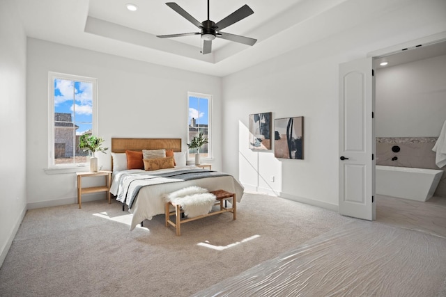 carpeted bedroom featuring a raised ceiling, ceiling fan, and multiple windows