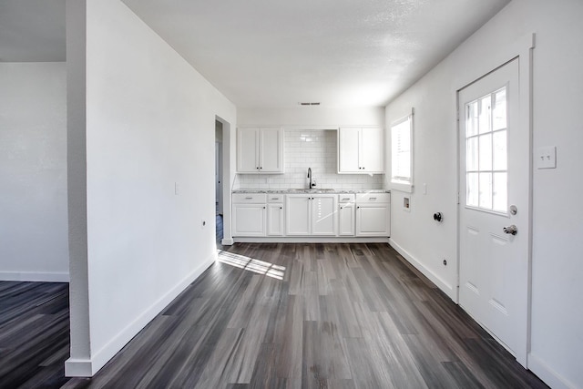 kitchen featuring tasteful backsplash, white cabinetry, sink, dark hardwood / wood-style flooring, and light stone countertops