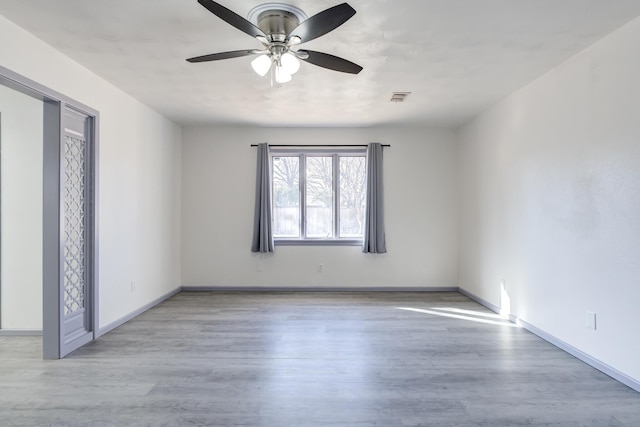 unfurnished room with visible vents, baseboards, wood finished floors, and ceiling fan