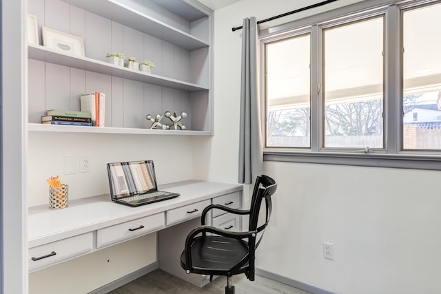 home office featuring built in desk, baseboards, and wood finished floors