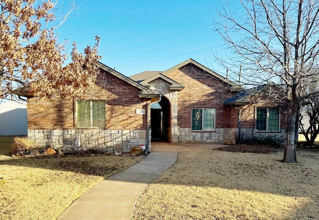 ranch-style home featuring stone siding, brick siding, and a front yard