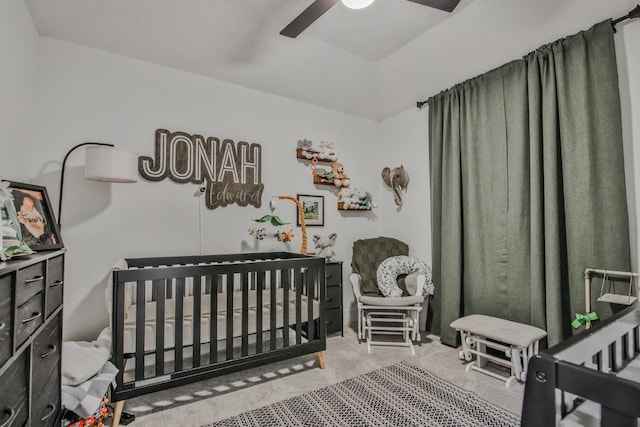 bedroom featuring carpet floors, a nursery area, and ceiling fan