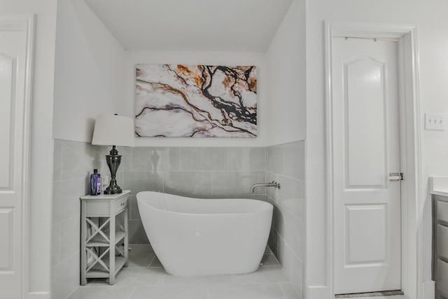 bathroom with vanity, tile walls, tile patterned floors, and a tub to relax in