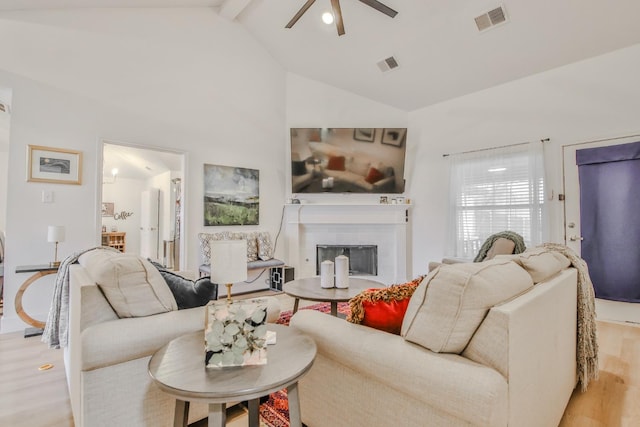 living room with beam ceiling, high vaulted ceiling, ceiling fan, and light hardwood / wood-style flooring