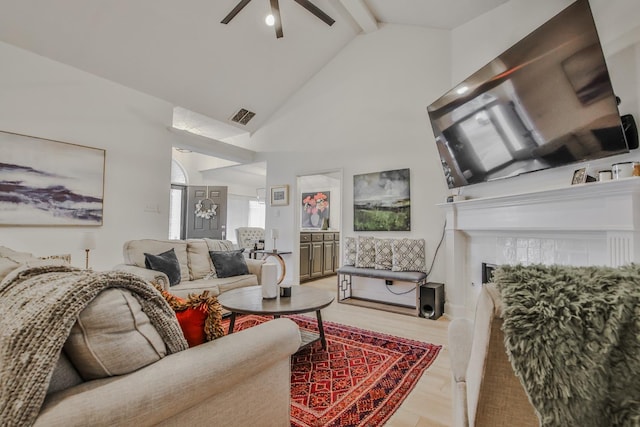 living room featuring a fireplace, high vaulted ceiling, beamed ceiling, ceiling fan, and light wood-type flooring