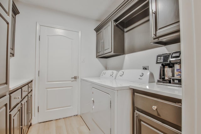 clothes washing area featuring light hardwood / wood-style floors, cabinets, and washing machine and clothes dryer