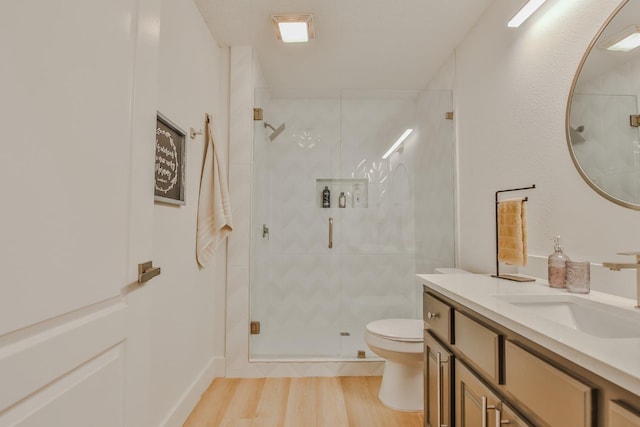 bathroom with vanity, hardwood / wood-style flooring, a shower with shower door, and toilet