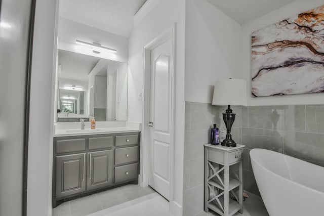 bathroom featuring a washtub, tile patterned flooring, tile walls, vanity, and a textured ceiling