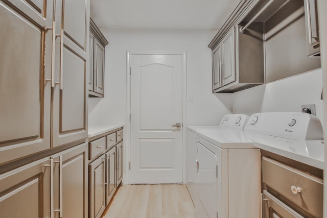 clothes washing area with cabinets, separate washer and dryer, and light hardwood / wood-style floors