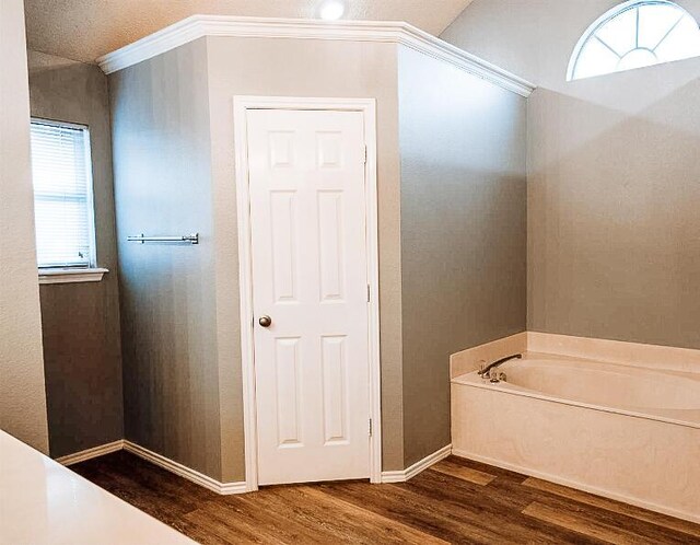 bathroom with crown molding, baseboards, a garden tub, and wood finished floors
