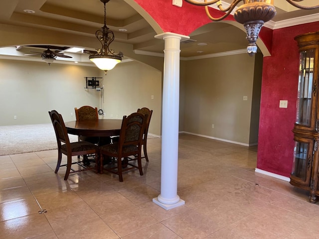 tiled dining space with decorative columns, ornamental molding, ceiling fan, and a tray ceiling