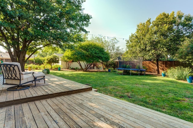 wooden deck with a yard and a trampoline