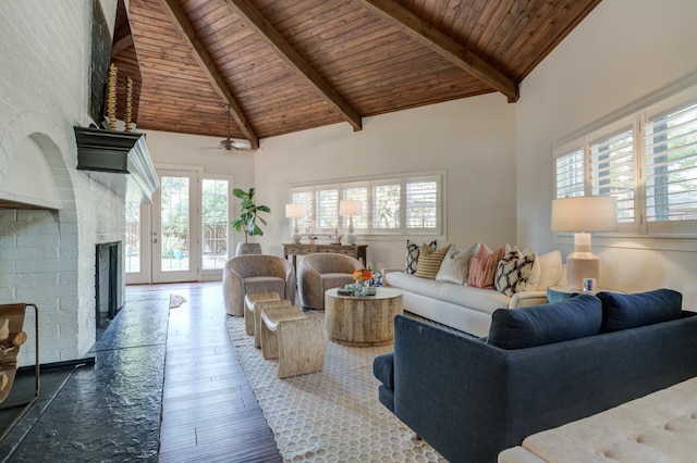 living room with hardwood / wood-style floors, beam ceiling, a wealth of natural light, and a brick fireplace