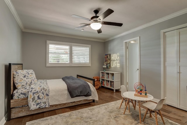 bedroom with dark wood-type flooring, ceiling fan, ornamental molding, and a closet