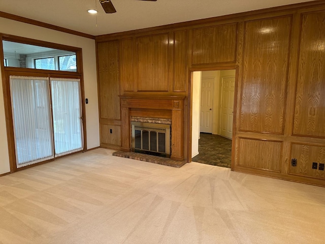 unfurnished living room featuring ceiling fan, light colored carpet, ornamental molding, and a brick fireplace