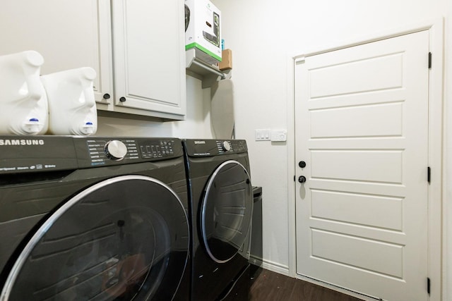 clothes washing area featuring dark wood-type flooring, cabinets, and washer and clothes dryer