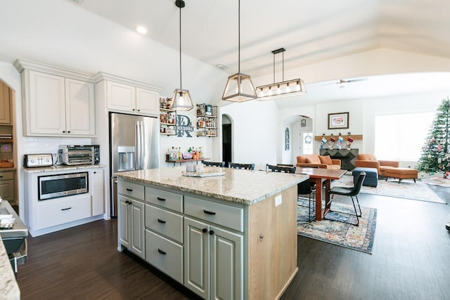 kitchen featuring vaulted ceiling, a kitchen island, pendant lighting, white cabinetry, and stainless steel appliances