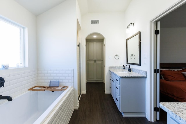 bathroom featuring vanity, tiled tub, and wood-type flooring