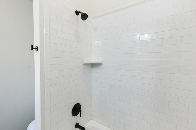 bathroom featuring tiled shower / bath combo and toilet