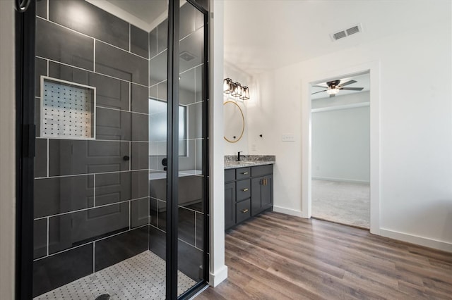 bathroom with vanity, hardwood / wood-style flooring, ceiling fan, and tiled shower