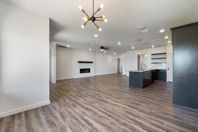 unfurnished living room with sink, ceiling fan with notable chandelier, and dark hardwood / wood-style floors