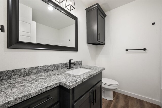 bathroom with vanity, toilet, and hardwood / wood-style floors