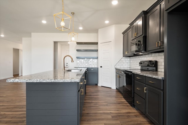 kitchen featuring sink, a kitchen island with sink, hanging light fixtures, dark hardwood / wood-style floors, and black appliances