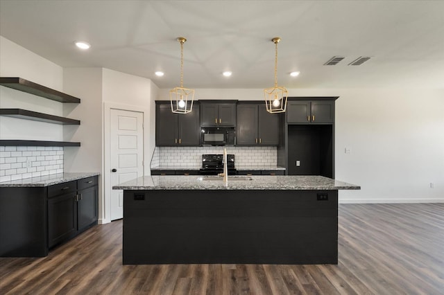 kitchen with decorative light fixtures, sink, a kitchen island with sink, light stone counters, and black appliances