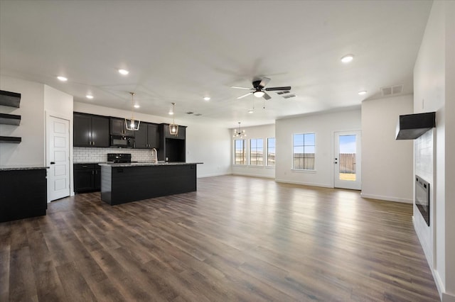 kitchen with tasteful backsplash, dark wood-type flooring, an island with sink, and black appliances