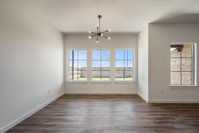 spare room featuring dark hardwood / wood-style flooring and an inviting chandelier