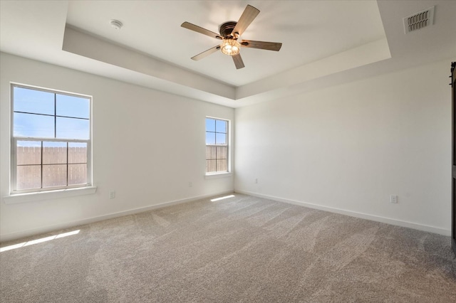 empty room featuring ceiling fan, carpet flooring, and a tray ceiling