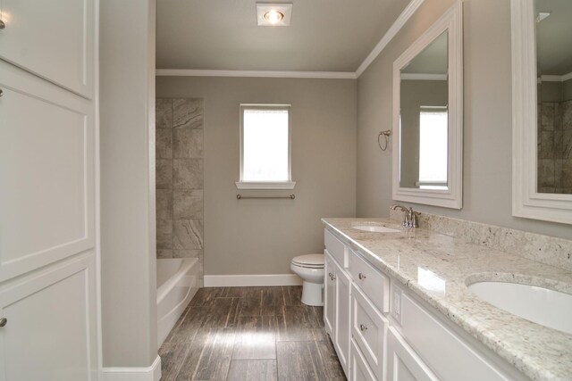 full bathroom featuring vanity, tiled shower / bath, crown molding, and toilet