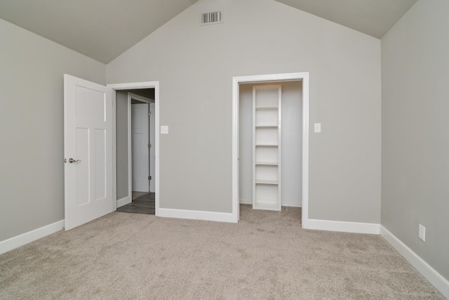 unfurnished bedroom with a walk in closet, vaulted ceiling, and light colored carpet