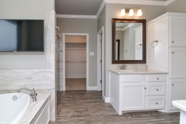 bathroom with ornamental molding, a bathtub, and vanity