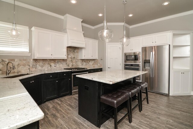 kitchen featuring sink, a breakfast bar, stainless steel appliances, a center island, and decorative light fixtures