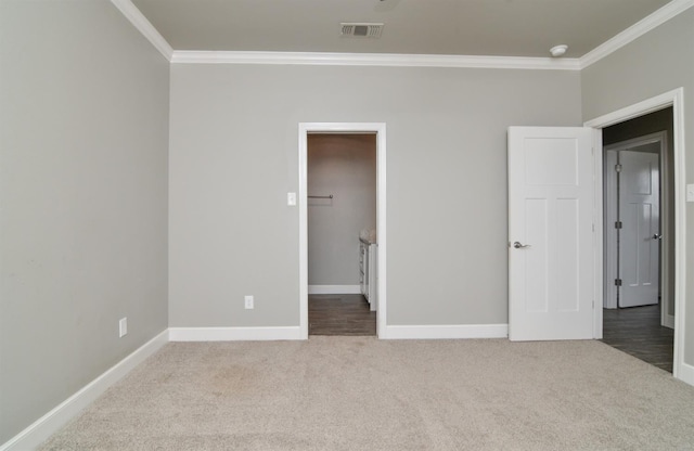 unfurnished bedroom with ornamental molding, a spacious closet, and carpet floors