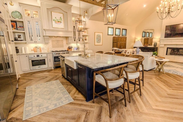 kitchen featuring high end stainless steel range, an island with sink, light parquet flooring, and white oven