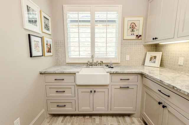 kitchen with light stone countertops, sink, and decorative backsplash