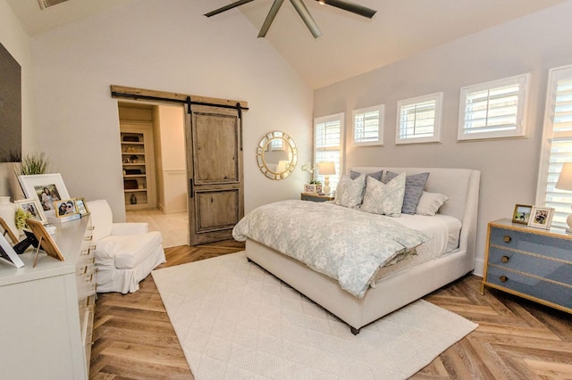 bedroom with parquet flooring, high vaulted ceiling, a barn door, and ceiling fan