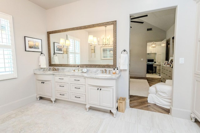 bathroom featuring vanity, ceiling fan with notable chandelier, and vaulted ceiling