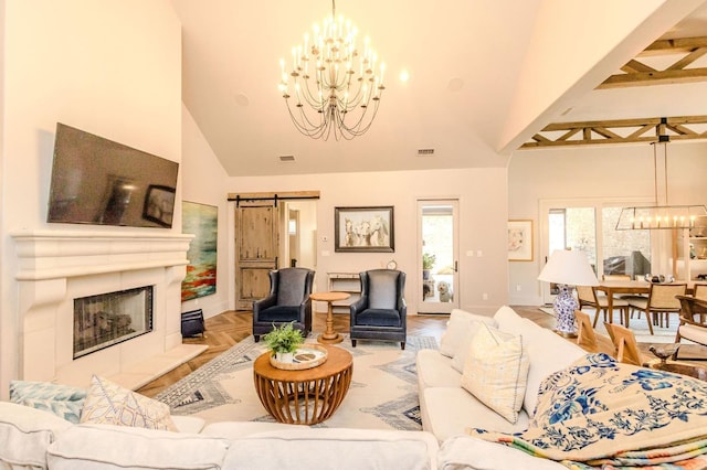 living room featuring parquet flooring, high vaulted ceiling, a chandelier, a tiled fireplace, and a barn door